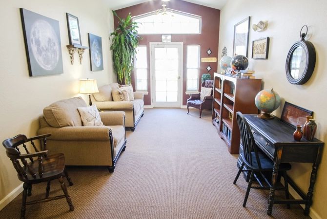 A cozy living room with comfortable seating, bookshelves, and ample natural light.