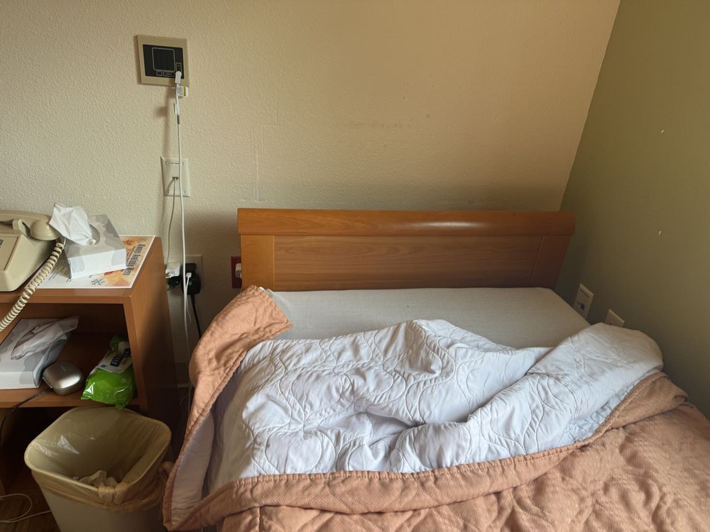 A hospital room featuring a bed with an IV stand and basic medical equipment.
