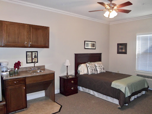 A cozy bedroom featuring a comfortable bed, a nightstand, and a small desk area.
