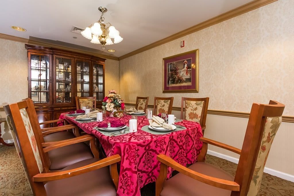 A formal dining room with a red tablecloth and elegant place settings.