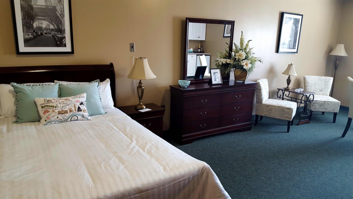 A cozy bedroom with a bed, dresser, and decorative elements.