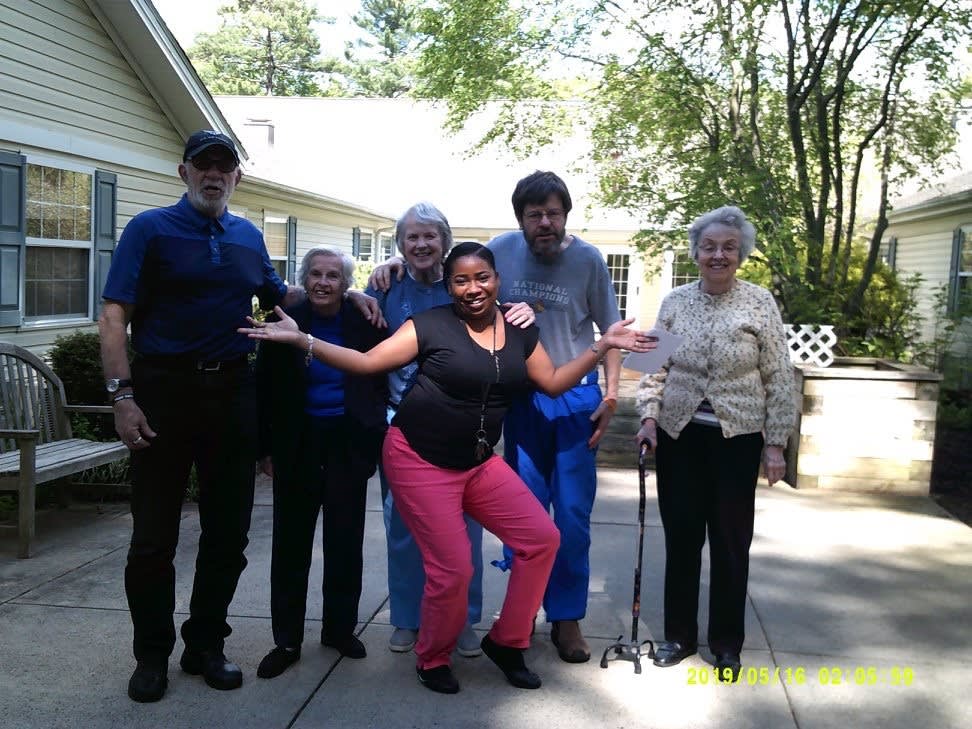 A group of people smiling and posing together outdoors on a sunny day.