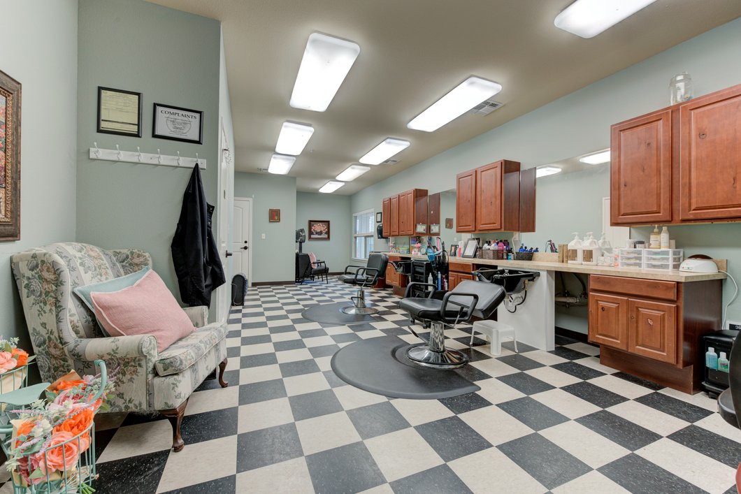 A modern barbershop with a checkered floor, styling chairs, and mirrors along the wall.