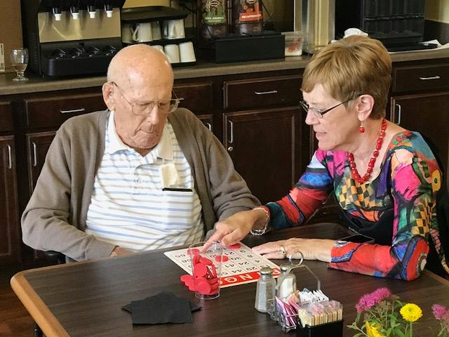 An elderly man receives assistance while playing bingo.