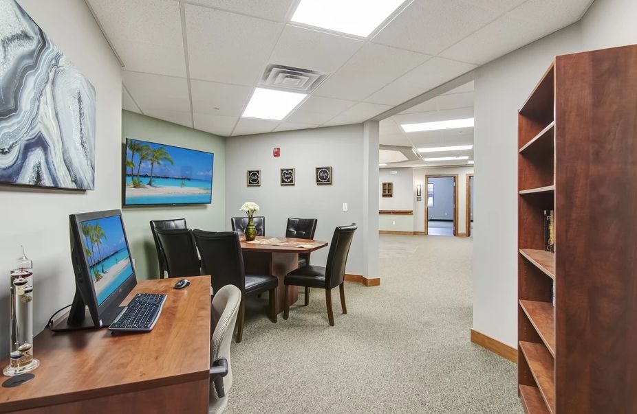A modern office meeting area with a conference table and computer desk.
