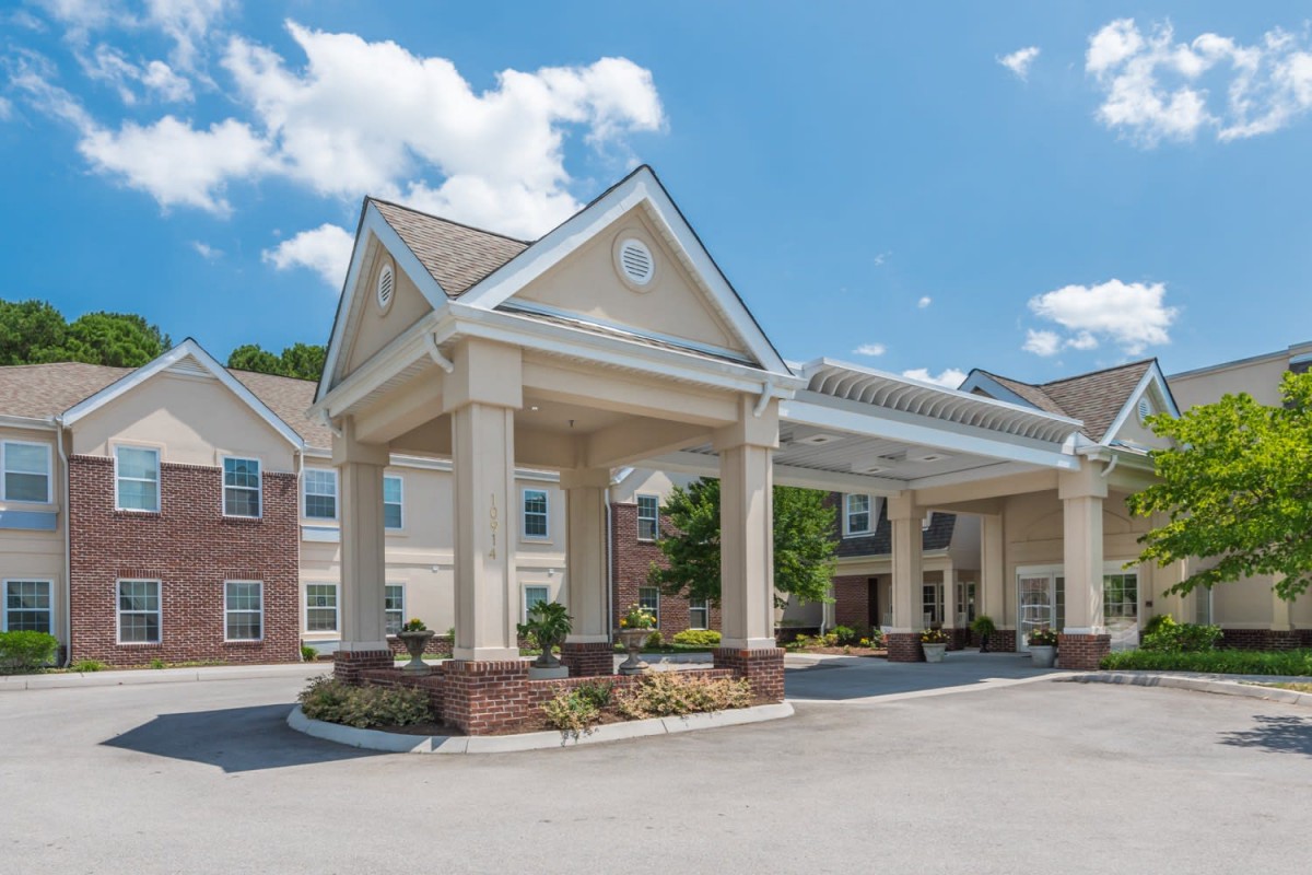 A large residential building with a covered entrance on a sunny day.