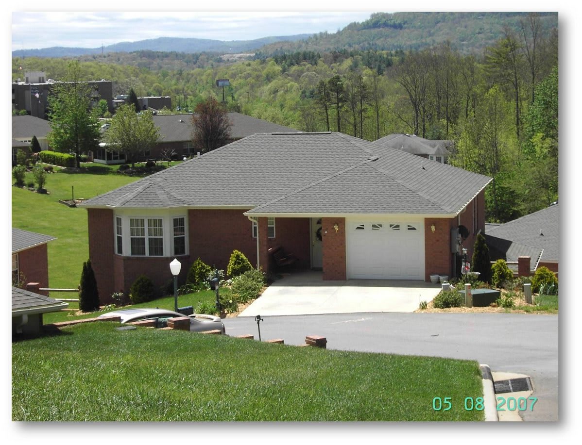 A suburban house with a spacious driveway, surrounded by greenery and scenic views.