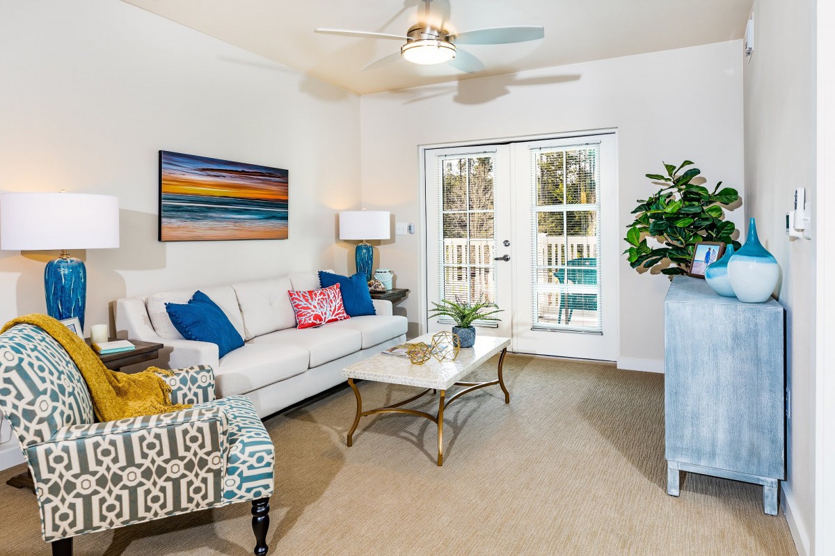 A modern living room featuring stylish furniture, colorful artwork, and a ceiling fan for a cozy atmosphere.