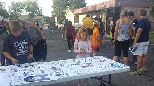 A lively outdoor community event with children engaging in various activities at a table.