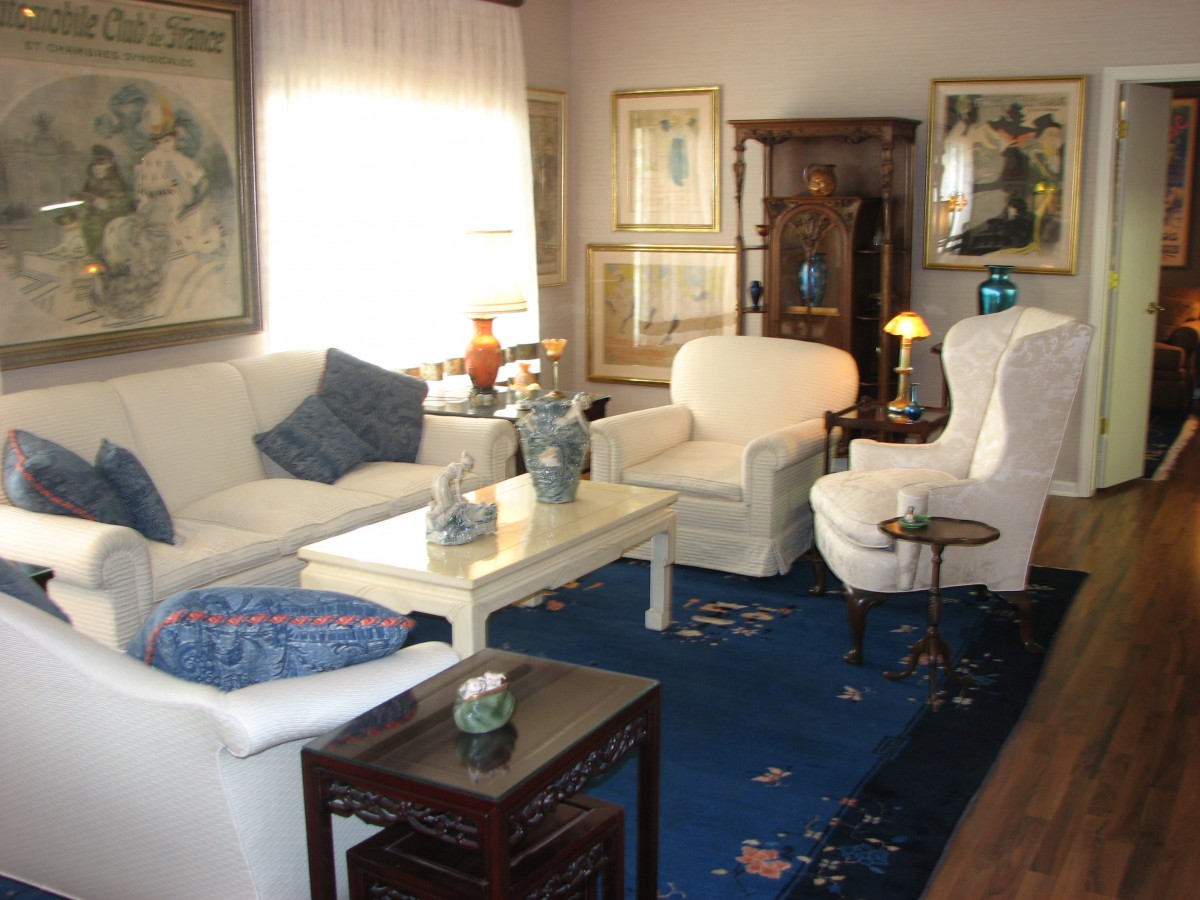 A cozy living room with white furniture and a blue rug.