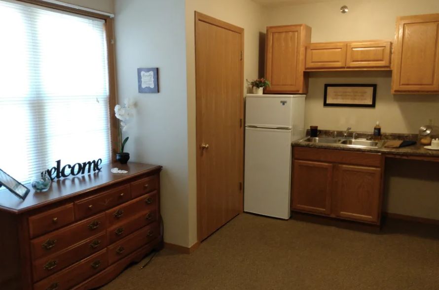A cozy apartment kitchen with wooden cabinets and a refrigerator.
