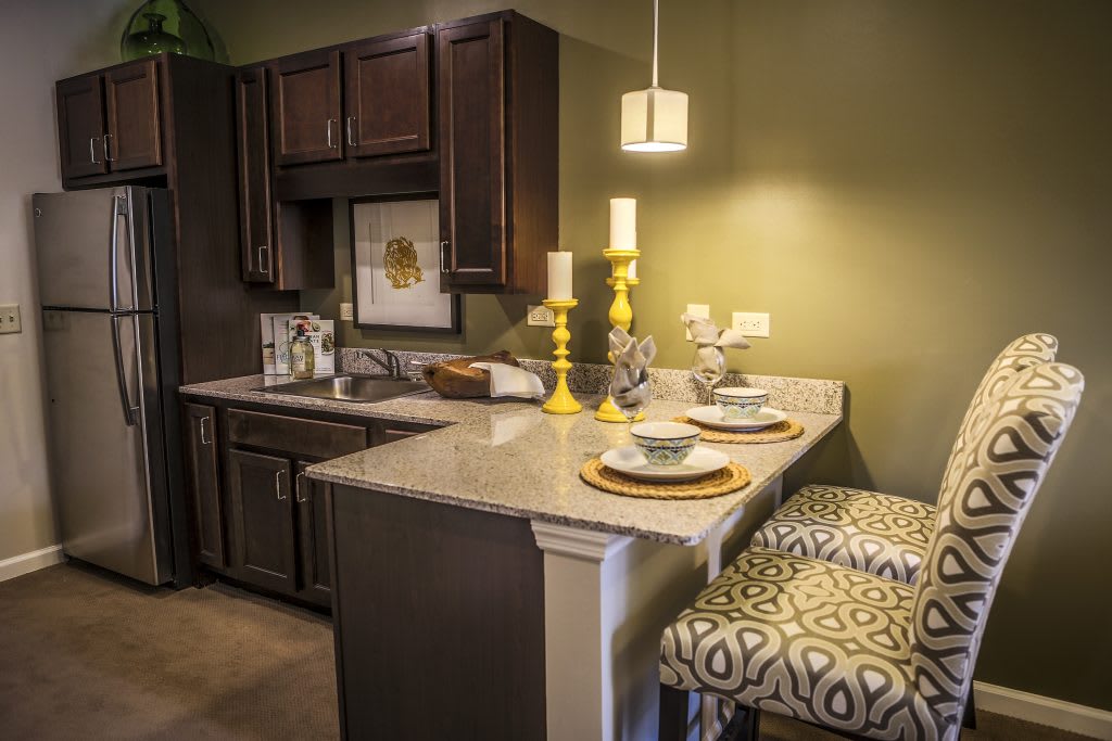 A cozy kitchen with dark cabinets, a marble countertop, and stylish bar stools.