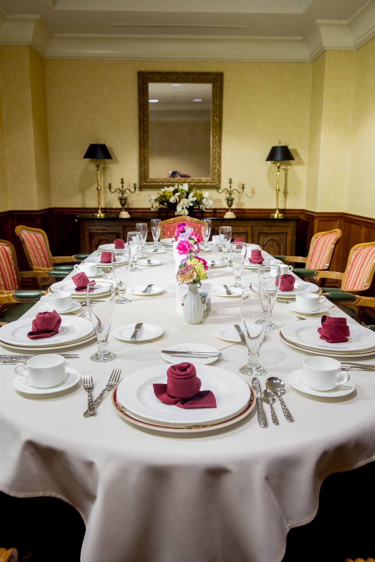 A formally set dining table with elegant dinnerware and napkins in a cozy interior.