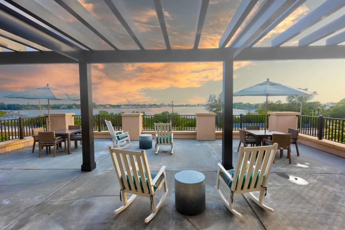 A peaceful patio with rocking chairs overlooking a lake at sunset.