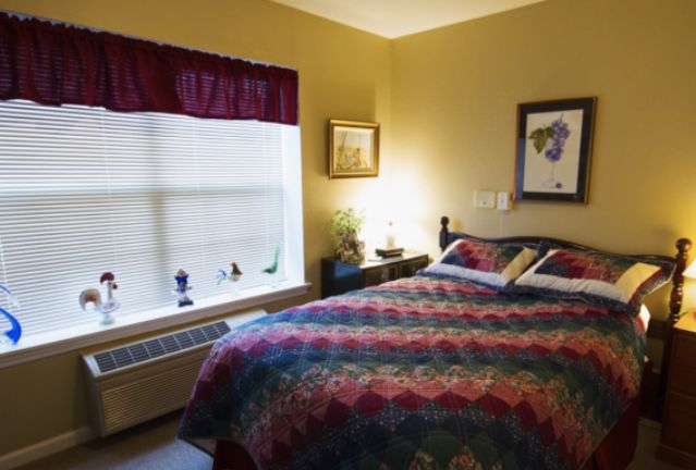 A cozy bedroom with a large bed, colorful bedding, and art on the walls.