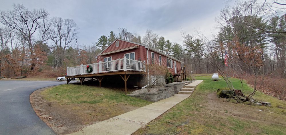 A cozy cabin with a large deck nestled in a rural, wooded area.