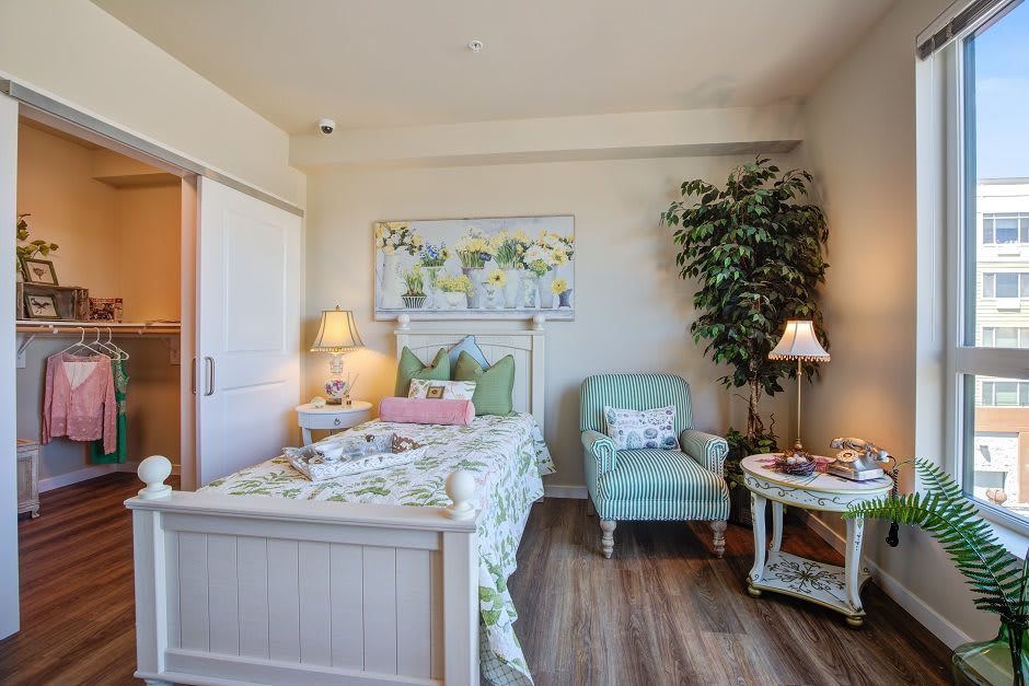 A cozy bedroom with a bed, armchair, and soft lighting.
