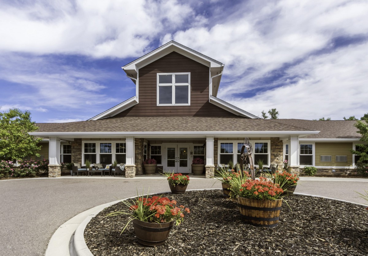A residential building with a landscaped entrance and cloudy sky.