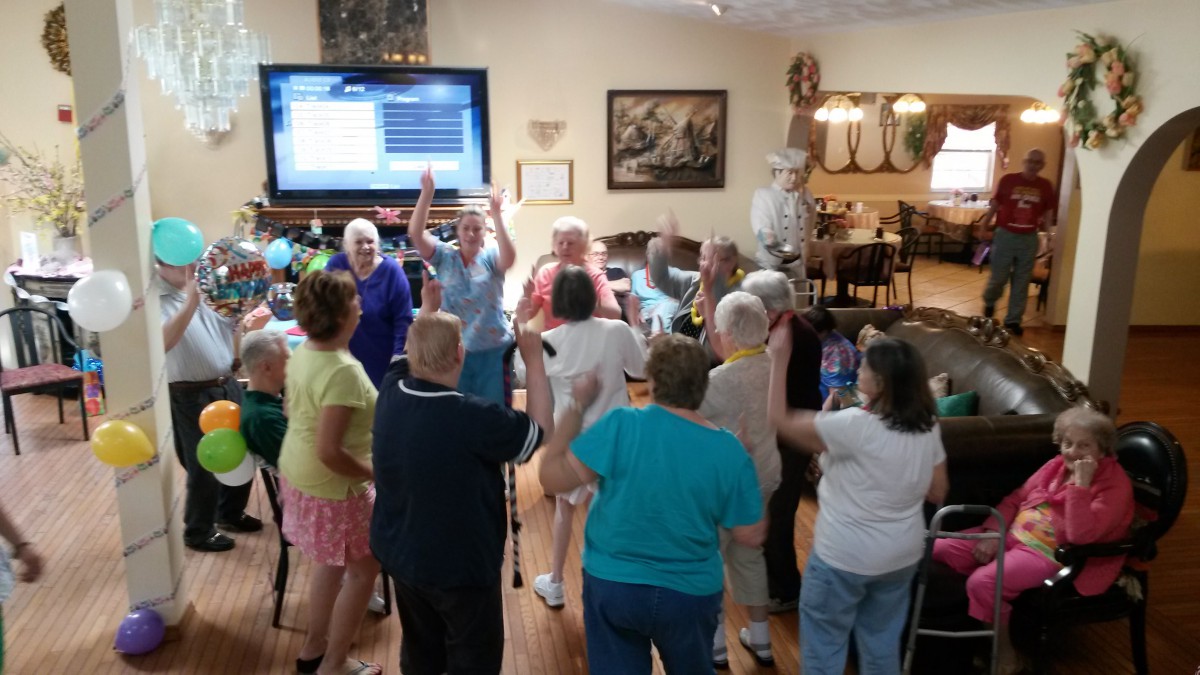 A group of seniors enjoying a gathering indoors, with a television in the background.