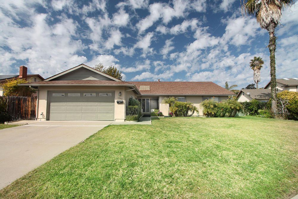 A suburban house with a well-maintained lawn and a cloudy sky overhead.