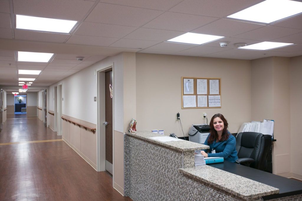 A receptionist sitting at the desk in a hospital corridor.