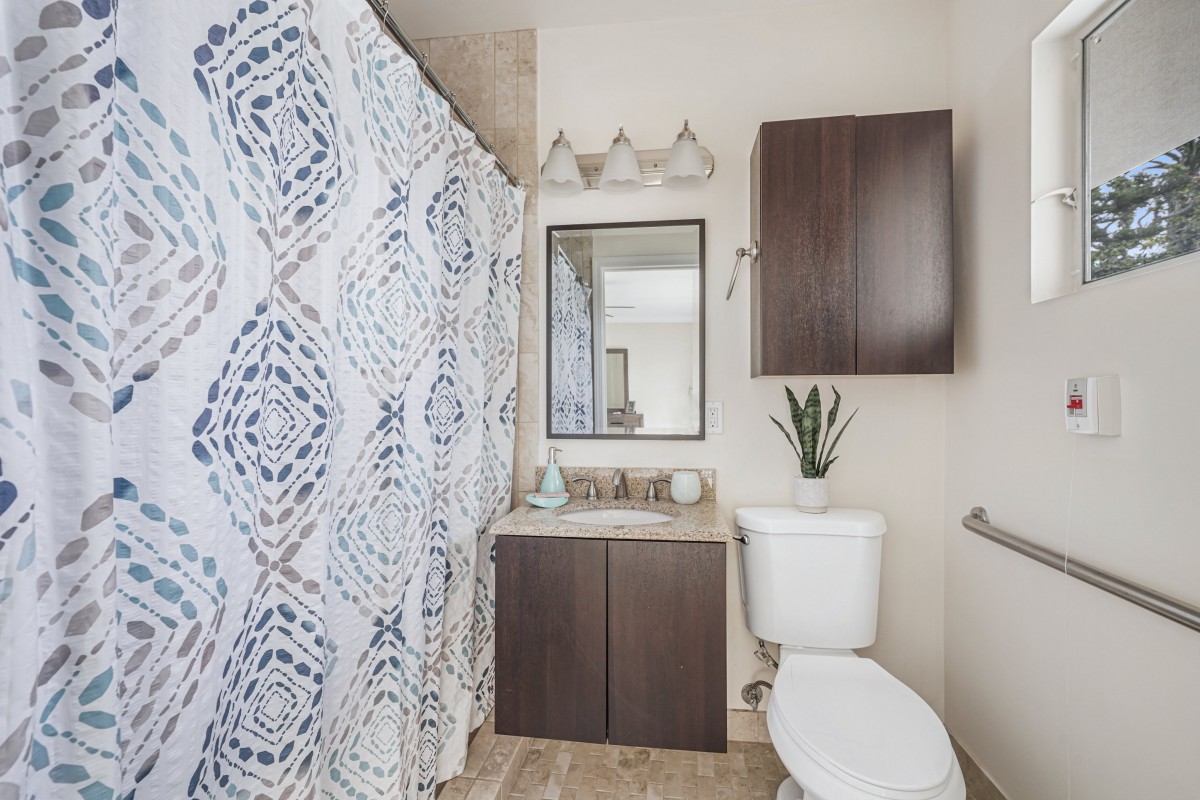 A modern bathroom with a patterned shower curtain and dark wood cabinetry.
