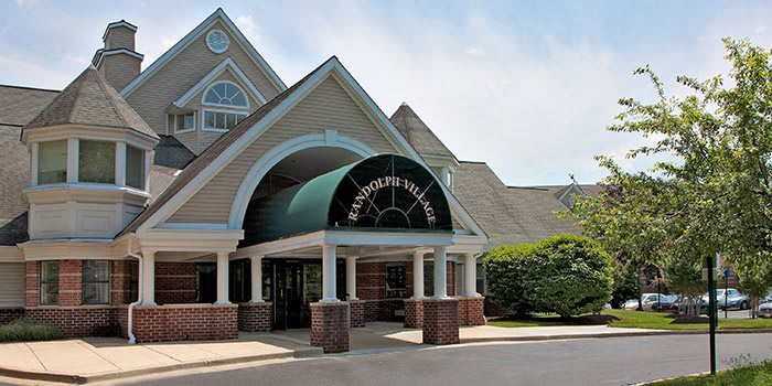 Entrance to a building with a green awning and brick facade.