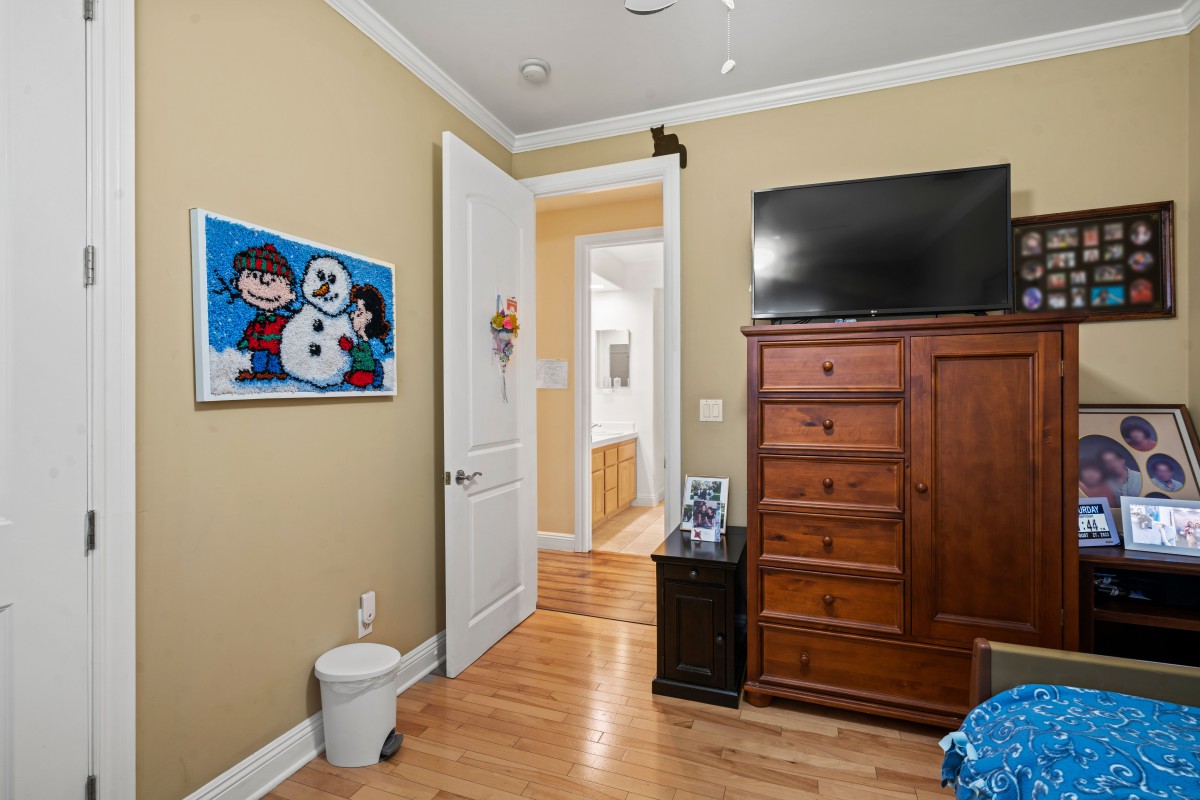A cozy bedroom with a dresser, TV, and artwork on the wall.
