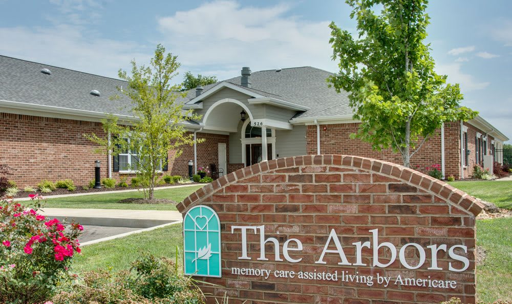 A brick building with a sign for 'The Arbor' surrounded by trees.