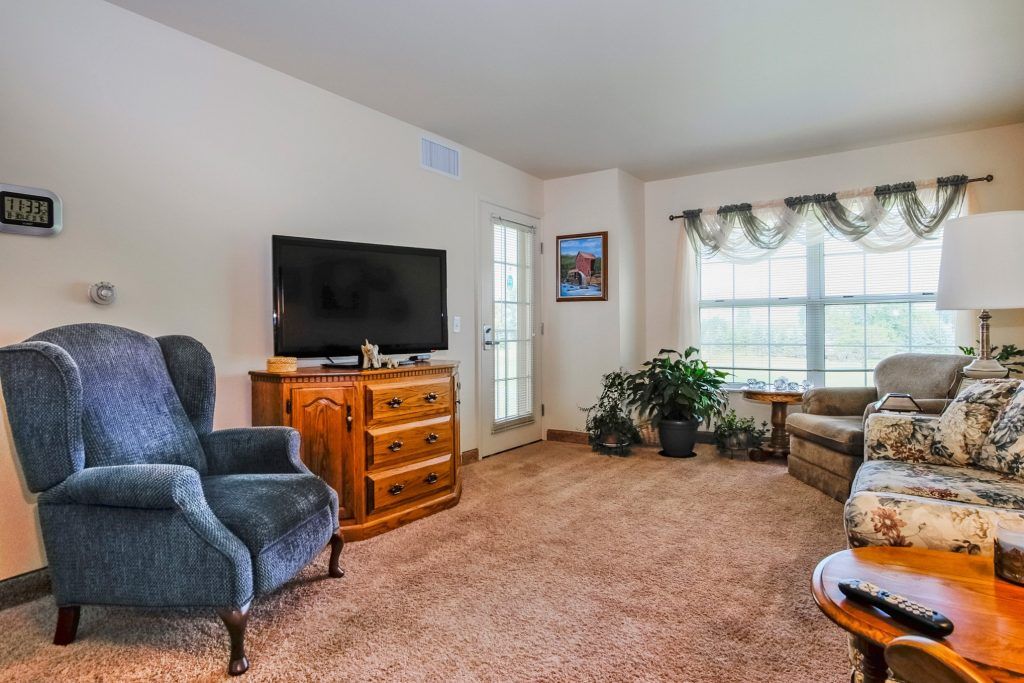 A cozy living room with comfortable seating, a television, and lush indoor plants.