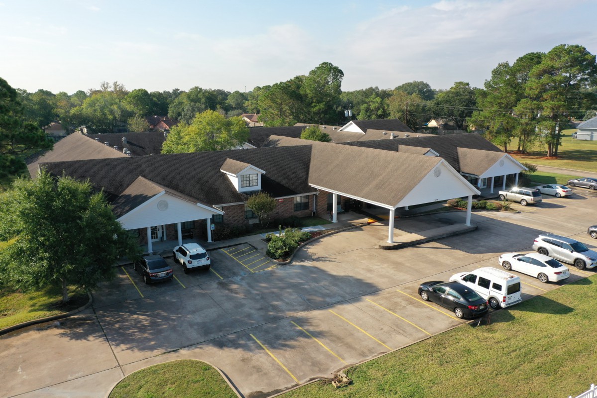 Aerial view of a suburban building with a parking lot and surrounding greenery.