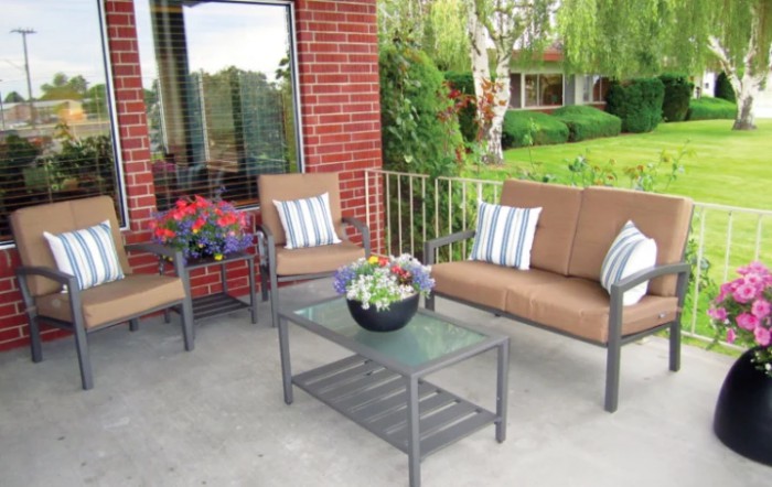 A cozy outdoor patio setup with chairs, a table, and potted plants against a brick wall.