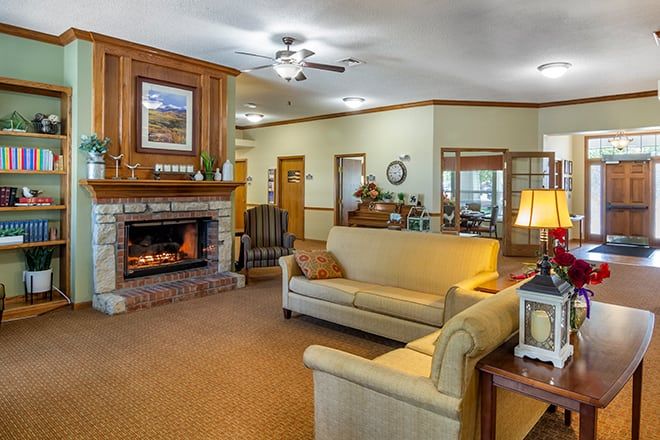 A cozy living room with a fireplace, featuring comfortable sofas and warm lighting.