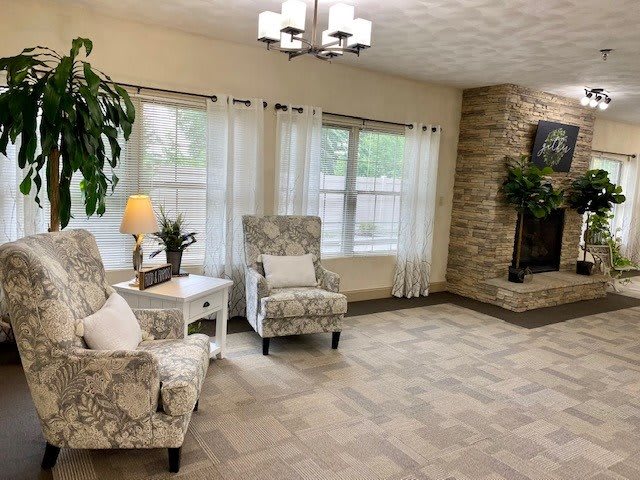A cozy living room with patterned chairs and a stone fireplace.