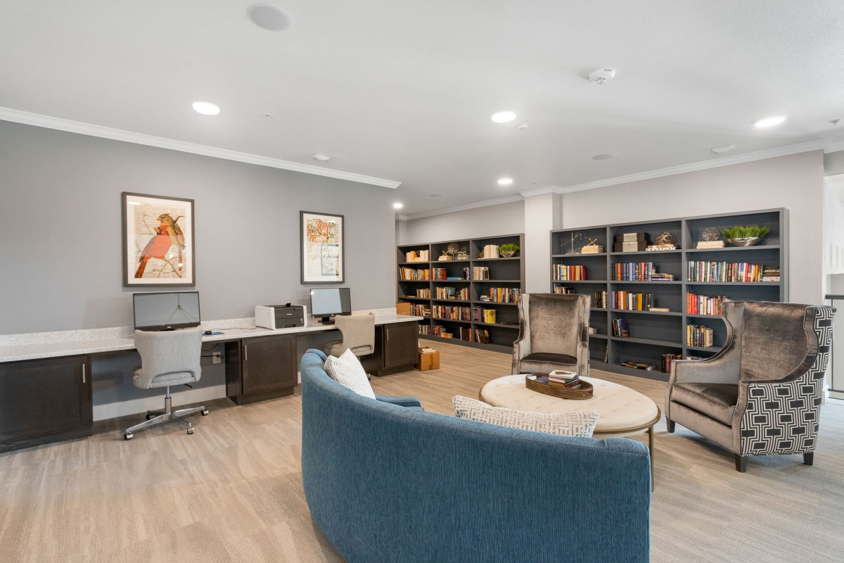 A modern library and workspace with bookshelves, desks, and comfortable seating.