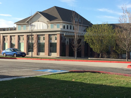 A modern building surrounded by a well-maintained lawn and parking area.