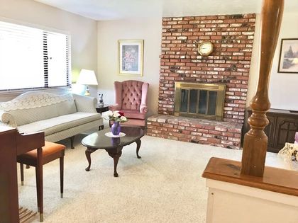 A cozy living room featuring a brick fireplace, a sofa, an armchair, and a coffee table.