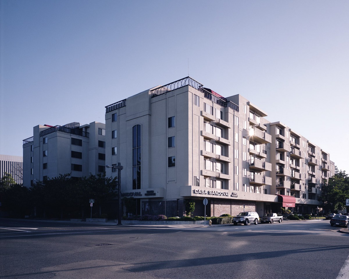A modern multi-story residential building on a city street corner.
