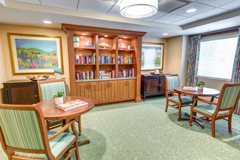 A cozy library room with bookshelves, tables, and chairs for reading.