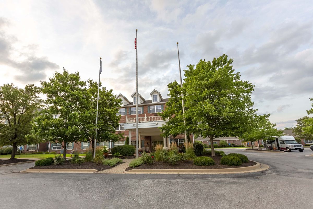 A hotel building with flags at the entrance, surrounded by trees and landscaping.