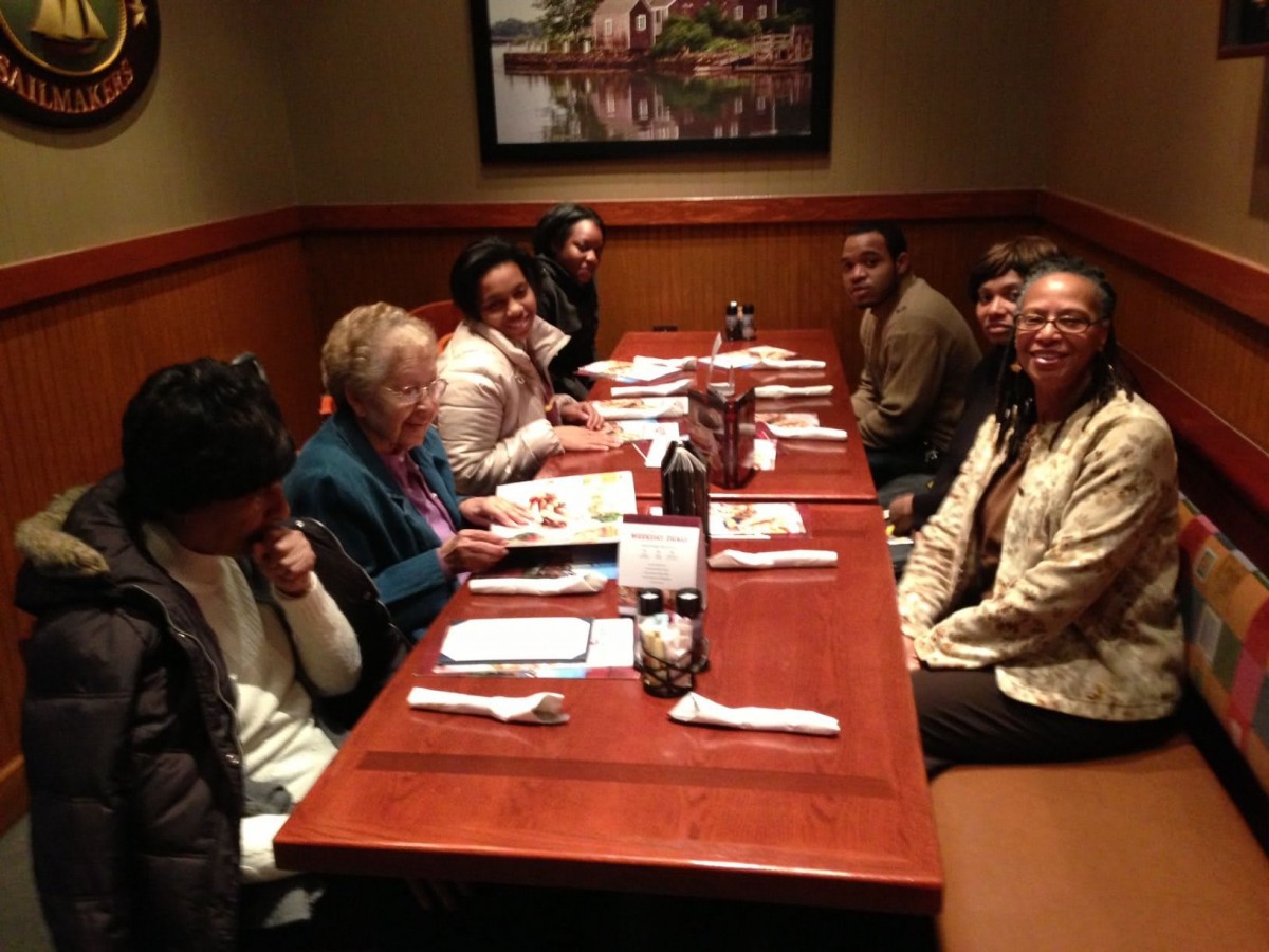 A group of people gathered around a table at a restaurant, enjoying each other's company.
