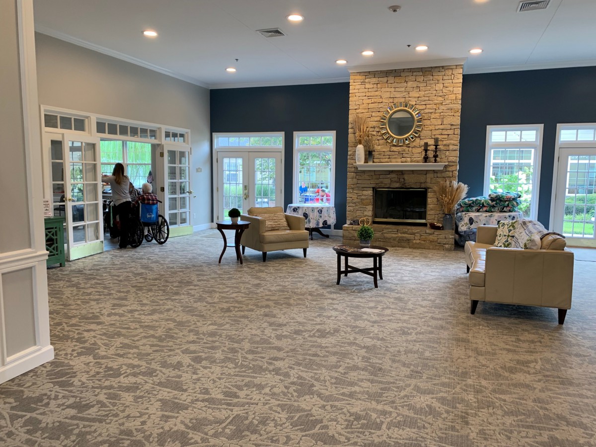 A spacious living room with a large stone fireplace, comfortable seating, and ample natural light.
