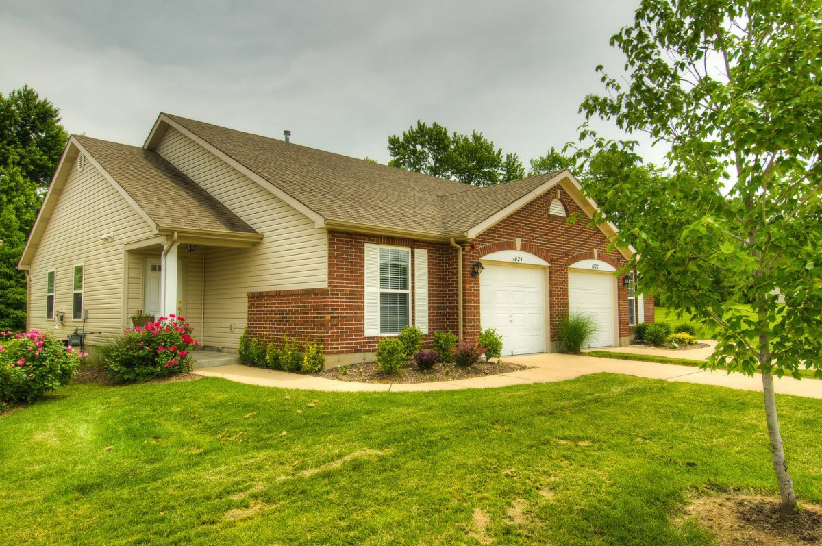 A suburban brick house with a well-maintained lawn and two garages.