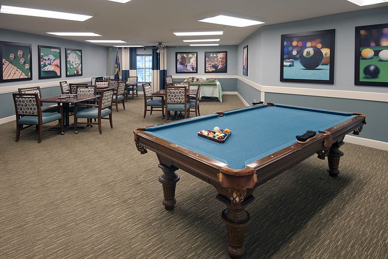 A well-furnished game room featuring a pool table and several seating areas.