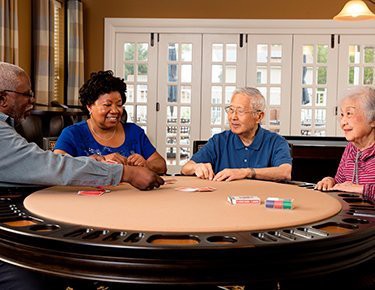 A group of seniors enjoying a game of poker around a table inside a cozy room.