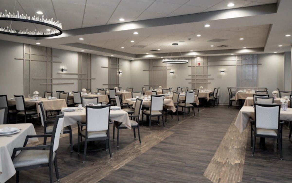 An elegant restaurant dining area with neatly arranged tables and chairs, featuring modern lighting.