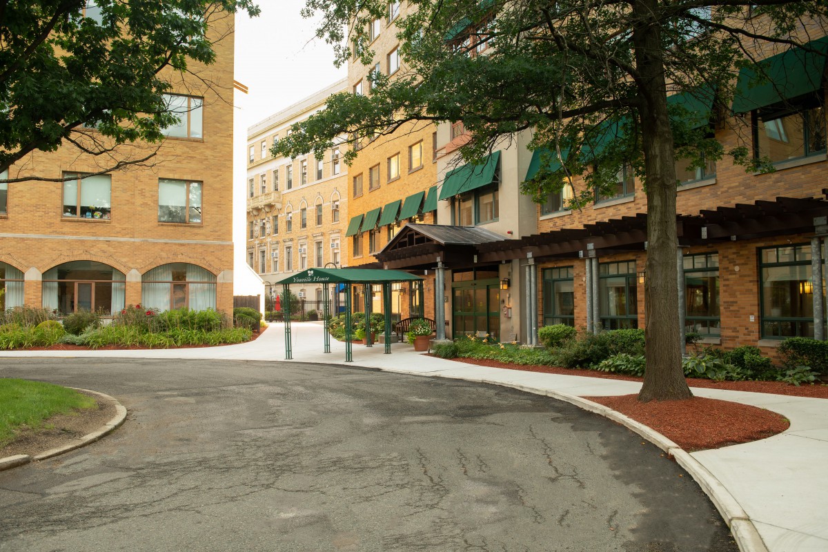A view of a building entrance with an awning and surrounding trees.