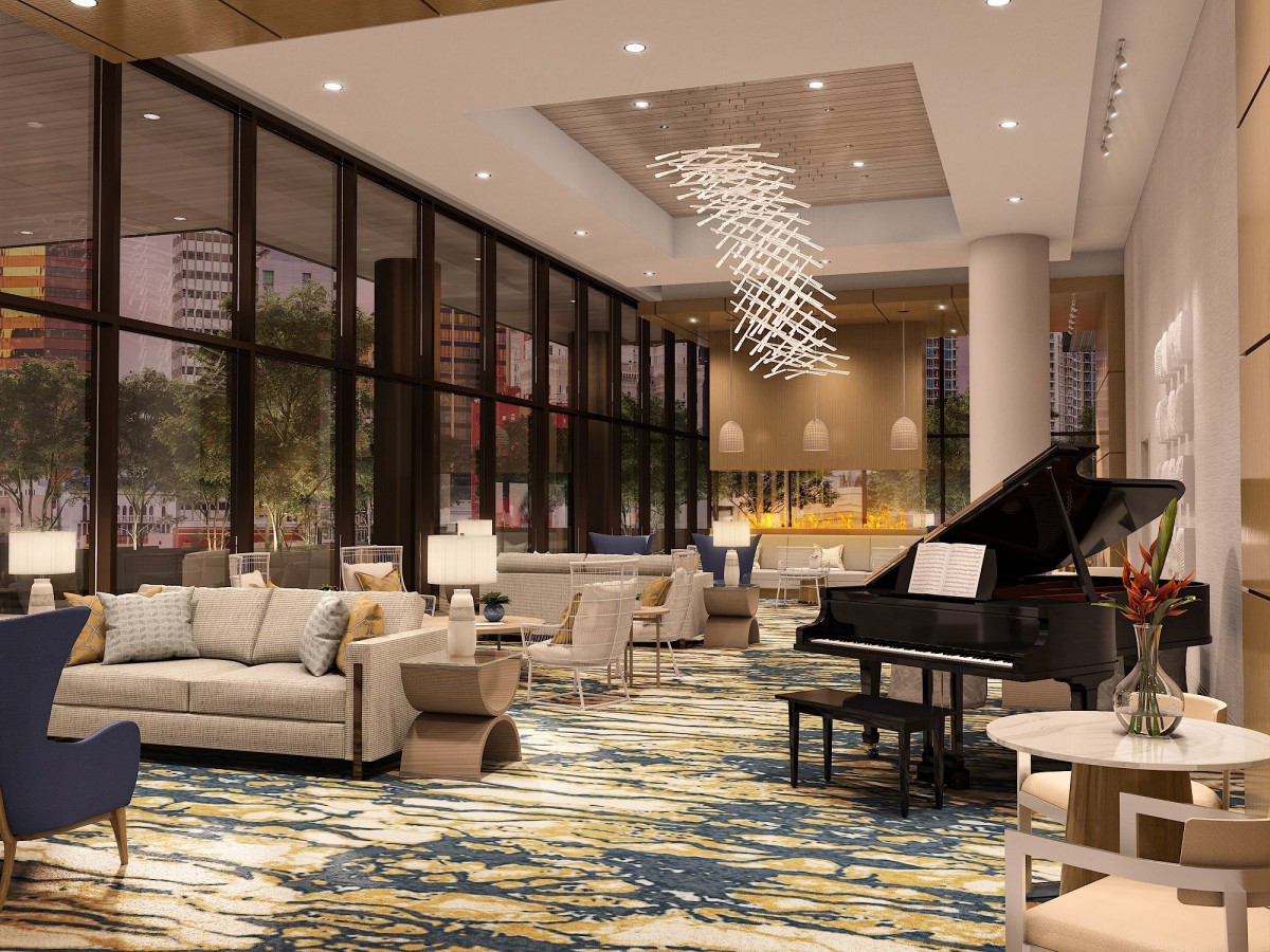 A spacious hotel lobby featuring elegant seating, a grand piano, and a contemporary chandelier.