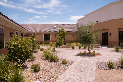 A serene outdoor pathway leads through a landscaped garden with a residential building in the background.