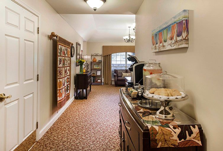 A cozy hallway with a snack and coffee station, decorated with artwork and carpeted flooring.